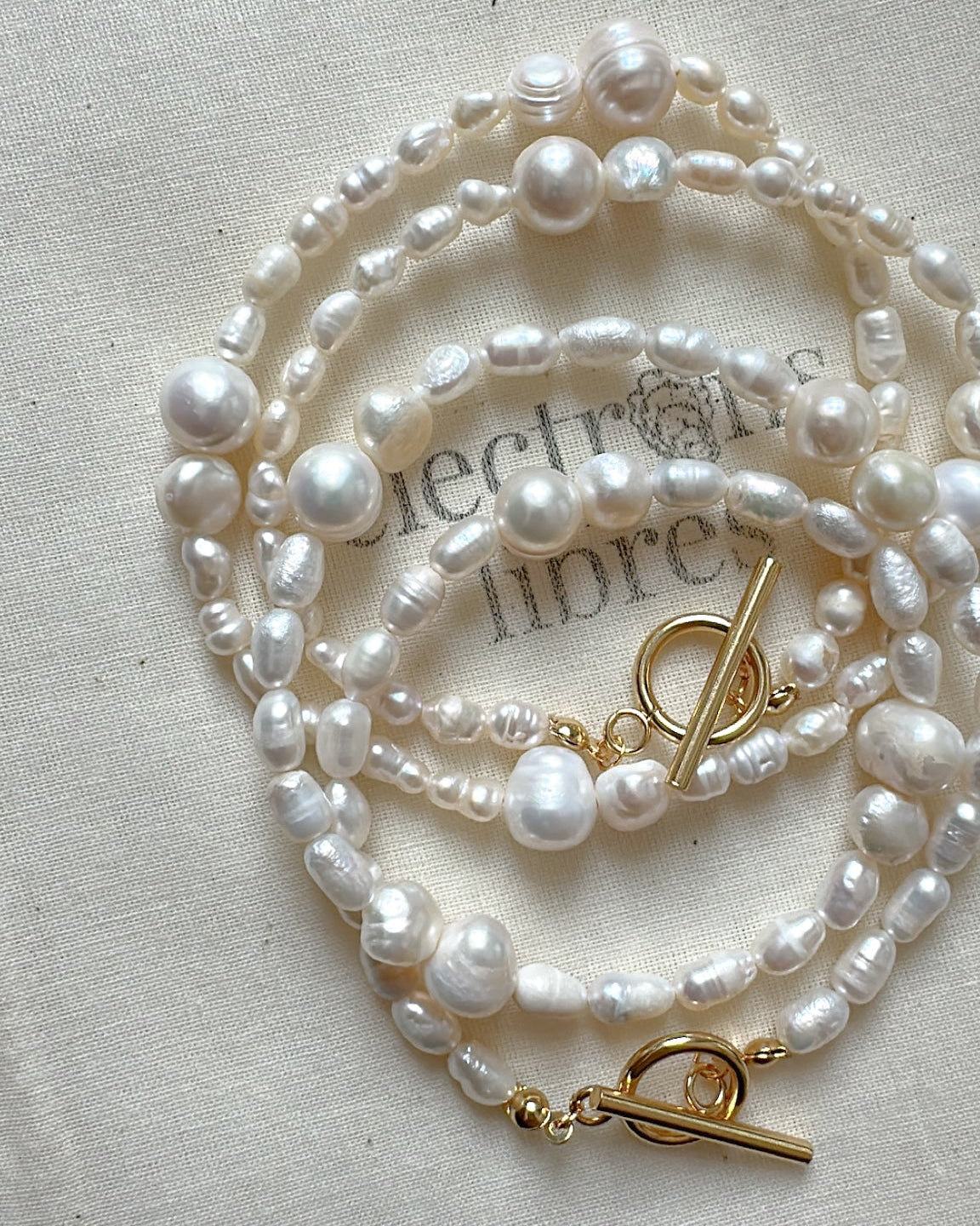 Set of pearl necklaces with gold clasp on a light fabric background